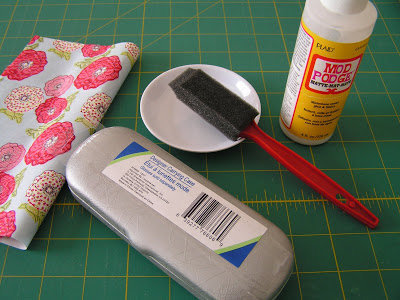 Il vous faut : un étui à lunettes, des tissus, un pinceau mousse, de la colle blanche et des rubans fins.