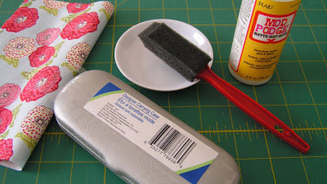 Il vous faut : un étui à lunettes, des tissus, un pinceau mousse, de la colle blanche et des rubans fins.