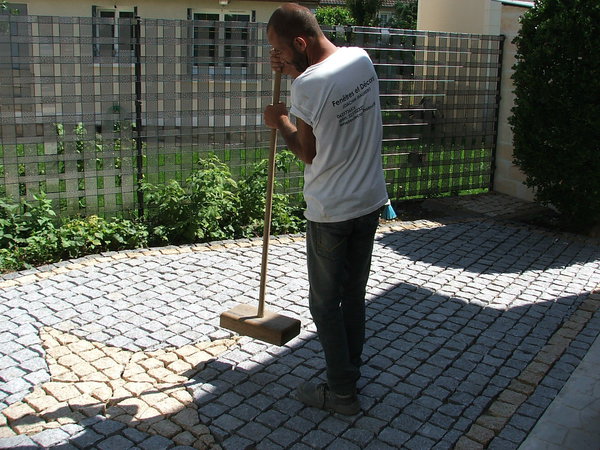 Etape 20 : Damer le pavage, afin de le compacter sur l’ensemble de la surface du terrain. Pour cela, utiliser un morceau de bois assez large et épais.