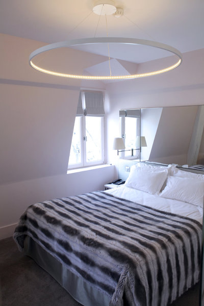 Autour du lit, la grande suspension équipée de Leds, le plaid en fausse fourrure et le miroir en triptyque créent un décor léger et confortable.