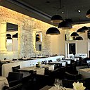 En noir et blanc, la brasserie fait référence au bâtiment historique avec le mur de pierre sèche, et les suspensions teintées d’or.