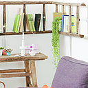 Un coin lecture agréable avec une étagère d'angle réalisée dans une vieille échelle.