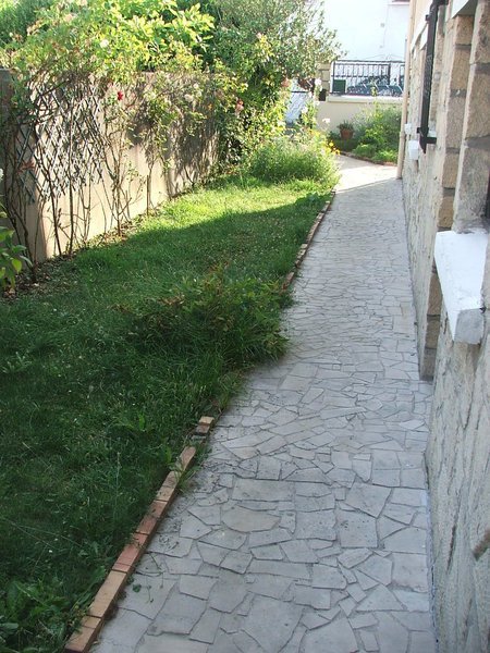 Avant, une allée de jardin dont l'état s'est dégradé avec le temps et qui ne délimite plus esthétiquement la zone piétonne du gazon.