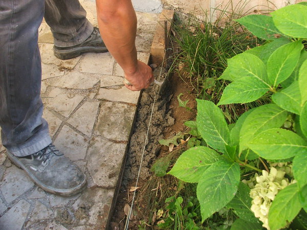 Etape 7 : Fabriquer un béton plus ou moins sec (5 volumes de sable, 2 volumes de ciment, 2 volumes d’eau). Étaler la préparation tout le long de la bordure, à même la terre. Progresser le travail par paliers de 1 mètre.