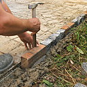 Etape 9 : La brique sera enfoncée en la tapotant légèrement avec le bout du manche en bois du marteau de maçon, dans le but de ne pas casser la brique, plus fragile que le pavé.