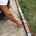 Etape 11 : Remplir de béton la petite distance entre l’allée et les pavés, dans le but de renforcer la prise ultérieure. Bien tasser le béton au fond de cet espacement.