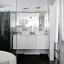 On retrouve le tandem noir et blanc dans la salle de bains. Baignoire îlot et meuble, Leroy Merlin. Vasque moulée en Corian©.