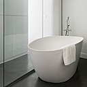 La chambre a été conçue comme une suite, avec une salle de bains aménagée derrière  une paroi en verre. Le rangement en tête de lit occulte la baignoire. Le lave-linge a trouvé sa place dans la salle de bains.