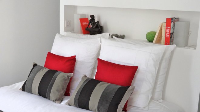 La tête de lit est percée d’une niche rectangulaire, tout en longueur, qui fait écho à celle du rangement de la pièce à vivre. Linge de lit, Descamps.