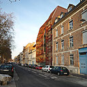 Façade sud avec vue de l’entrée et son volume en retrait. De ce côté de la rue, le bloc bureau est protégé par une double peau en résille métallique.
