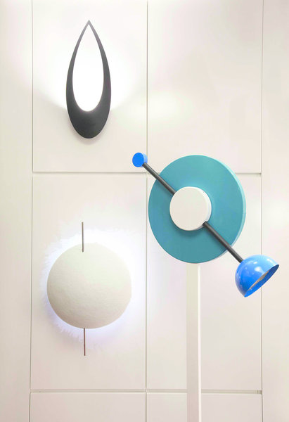 Dans la boutique Astéri, les appliques contemporaines côtoient des lampadaires mythiques, à l’image du lampadaire Charleston, dessiné en 1984 par Martine Dedin pour Memphis Milano. Au mur, Blum chez Lumen Center est une applique majestueuse aux allures de masque africain ; et PK Led chez Catellani & Smith, une applique décorative en forme de boule qui crée un jeu de lumières étonnant, donnant l’impression que le mur est peint par le reflet de la lumière.