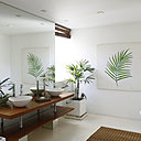 Le sol de la salle de bains, équipée d’un hammam, est entièrement en béton. La colonne présente dans l’espace, sert de support à des étagères de rangement en bois exotique.