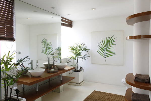 Le sol de la salle de bains, équipée d’un hammam, est entièrement en béton. La colonne présente dans l’espace, sert de support à des étagères de rangement en bois exotique.