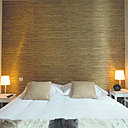 Les matériaux bruts trouvent aisément leur place dans les chambres ambiance nature, à l’image de cette tête de lit composée de baguettes de bois, et du jeté de lit en peau naturelle.