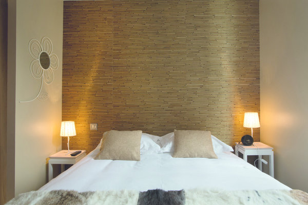 Les matériaux bruts trouvent aisément leur place dans les chambres ambiance nature, à l’image de cette tête de lit composée de baguettes de bois, et du jeté de lit en peau naturelle.