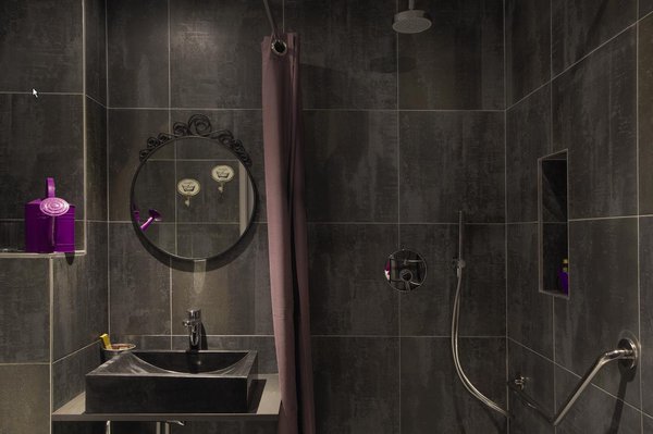 Les salles de bains sont aussi élégantes que les chambres, avec une décoration très simple dans des tons pourpre, qui se marient parfaitement avec un carrelage mural gris anthracite.