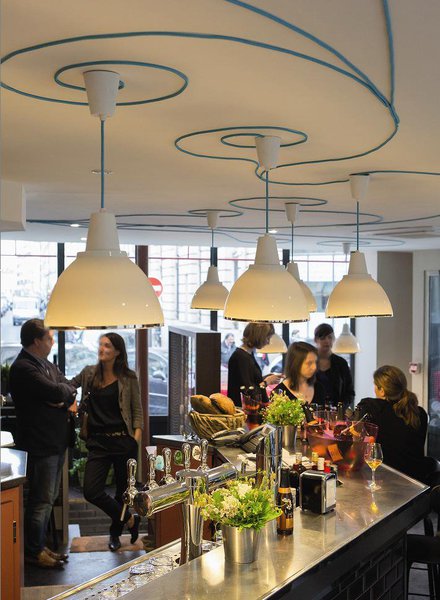 Le restaurant est placé sous le signe de la « bistronomie ». Avant de passer à table, et de découvrir les fameux tapas de Flora Mikula, prenez place autour du bar de cinq mètres, seul vestige de l’ancien établissement, habillé d’un carrelage métro irisé, et éclairé par des saladiers Bernardaud usinés, faisant office de suspensions.