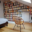Le mur de livres suit la pente du toit et encadre le radiateur.
