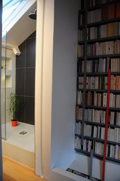 Dans la partie la plus haute de la pente du toit, une douche carrelée à l’italienne a été créée pour optimiser l’espace qui s’ouvre sur la chambre, simplement séparée de la salle de bains par une porte en verre.