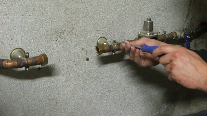 Etape 11 : les raccords flexibles nécessitent des raccords mâles. Il est donc nécessaire de démonter le système qui a permis l’installation de l’ancien filtre. Dévisser le collier de serrage du tuyau en cuivre à l’aide d’un tournevis.