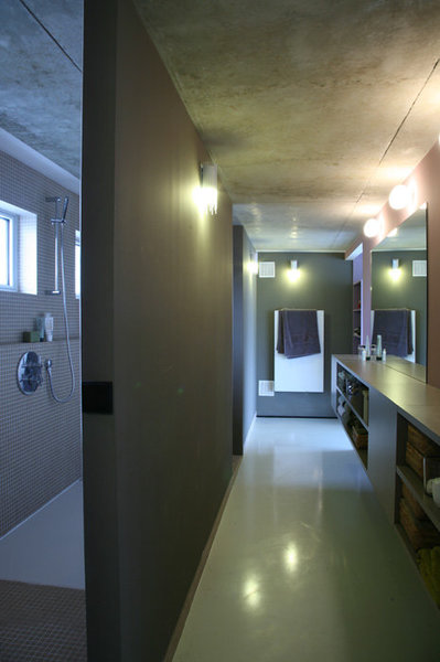 Derrière le lit, des cloisons cachent la salle de bains, et servent de support et coffrage aux éléments  sanitaires. L’espace a été travaillé linéairement en accord avec le volume existant.