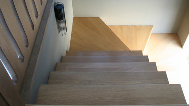 L’escalier en chêne est encadré dans une cage ajourée qui fait écho au porte-manteau de l’entrée.