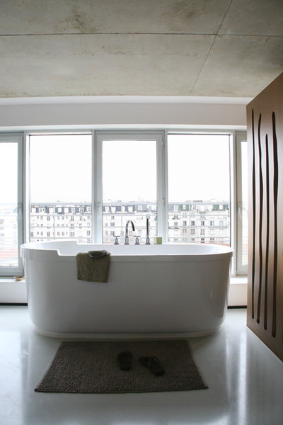 La baignoire de la suite principale, en îlot, offre une position stratégique pour admirer les toits de Paris. Les panneaux de la cage d’escalier, à proximité, assurent l’intimité de l’espace.