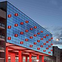 Le rouge donne le ton avec des « fanions » lumineux en verre fixés sur le mur rideau de la façade d’entrée. Ils servent de repère visuel dans la ville.