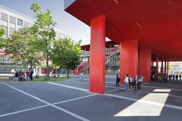 Le vaste porche théâtralisé assure désormais plusieurs fonctions. La grande sous-face en résille métallique rouge du laboratoire devient un vaste porche. Il abrite le nouveau hall d'entrée conçu dans une courbe vitrée, et prolonge la salle de conférence. Il offre aussi aux élèves de l'établissement le préau couvert qui leur manquait. La lasure rouge des poteaux du porche accompagne le cheminement depuis la rue jusqu’à la cour.