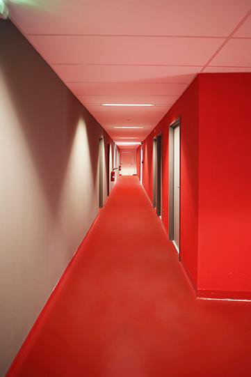 A l’intérieur des bâtiments, le rouge est aussi un élément signalétique fort. Il nappe les espaces avec un linoléum rutilant pour les couloirs et circulations, dans le nouveau bâtiment STL, comme dans les anciens.