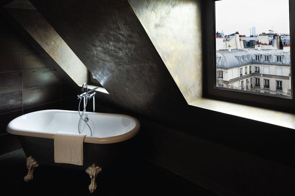 Au 6ème étage de l’hôtel, les murs sont recouverts d’une couleur bronze patinée aux effets de tadelakt marocain. Mi-contemporaine, mi-classique, la baignoire, dessinée par Stella Cadente pour l’éditeur belge Aquamass, s’intègre parfaitement à la chambre.