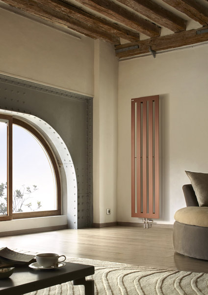 Lignes tendues pour le radiateur Karena en finition cuivre qui font écho aux poutres anciennes du plafond en apportant une belle modernité.