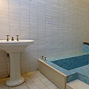 La chambre parentale est agencée comme une suite avec une salle de bains attenante cachée derrière un rideau. La baignoire creusée dans le sol est entièrement carrelée. Un lit de repos l’accompagne comme dans un spa ou un hammam.