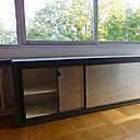 Des rangements  aux façades coulissantes gain de place occupent le dessous des fenêtres en bandeau.