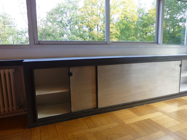 Des rangements  aux façades coulissantes gain de place occupent le dessous des fenêtres en bandeau.