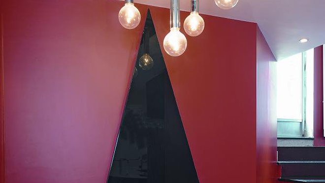 Ultra design et original, le radiateur sculpture Triangle de Michel Cinier, réalisé à la main à partir de la pierre Olycale,  une pierre naturelle pyrénéenne concassée et restructurée, et en verre émaillé Sécurit. Disponible en rouge, noir ou bronze.