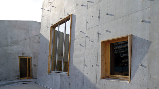 Le béton des façades et de la toiture est brut, avec les rebouchages des trous de banche (coffrage) en saillie. Les baies vitrées sont encadrées de bois.