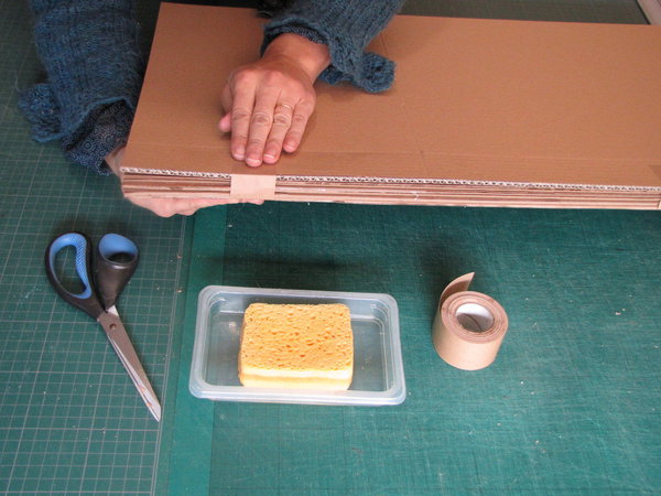 Etape 3. Assemblez les 3 plaques en un paquet serré, grâce à 8 morceaux de kraft gommé. (Sur l’image, nous avons ajouté une quatrième plaque de carton, pour réaliser un gabarit supplémentaire, quoique facultatif).