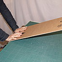 Etape 16. Pour courber la bande de carton, cassez le carton, cannelure après cannelure, le long du bord droit d’une table, en appuyant avec les paumes des mains.