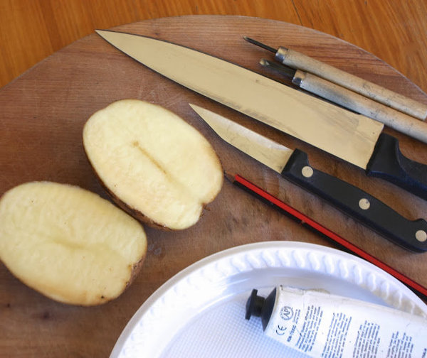 Le matériel qu'il vous faut : une pomme de terre, des couteaux, une gouge, une assiette en plastique, de la peinture, et du papier absorbant.