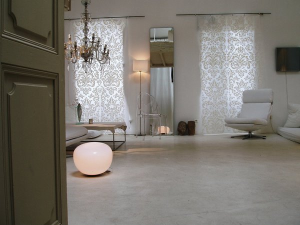 Dans ce salon, on a décliné les blancs dans une palette de matières qui s’offrent en camaïeu raffiné. Béton blanc au sol, rideaux en coton peint, travaillés comme des toiles brodées fin XIXème, cuir immaculé du fauteuil, cristal du lustre, polycarbonate transparent de la chaise Louis Ghost…