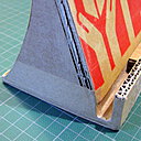 Etape 8 : Découpez des morceaux de papier kraft gommé. Humidifiez la face brillante en passant le morceau de kraft sur l’éponge humide. Recouvrez soigneusement votre construction, au niveau de chaque découpe, de chaque jonction pour avoir des côtés bien uniformes et masquer ainsi les inscriptions non désirées.