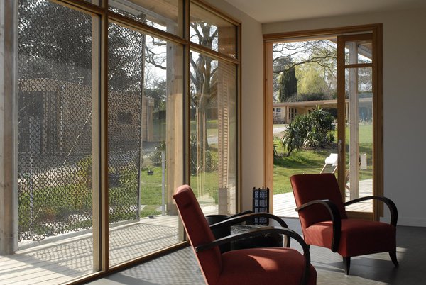 Une baie à galandage assure la liaison avec la terrasse. Les menuiseries extérieures en chêne dialoguent avec le parquet également en chêne massif.