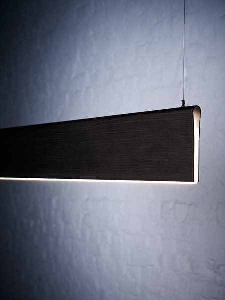 La suspension Piega Luce est composée d'une pièce de bois unique dont la teinte est blanche, noisette, ou noire.