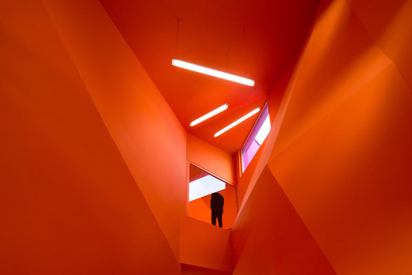 Le orange vif inonde les espaces de circulation et crée un environnement abstrait et immersif pour les usagers.
