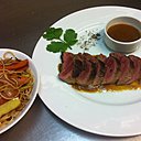 Les magrets de canards sont servis avec une sauce au miel et des nouilles sautées à l'asiatique.