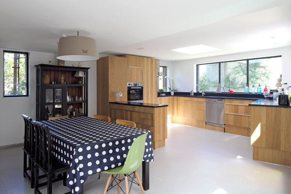 Totalement intégrée avec son plan de travail en granit noir, la cuisine s’ouvre à la fois sur la pièce à vivre et sur la terrasse pour prendre facilement ses repas dehors aux beaux jours.