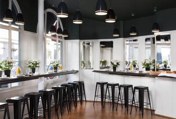 La salle de petit-déjeuner est conçue comme un bar avec des hauts tabourets de style industriel (Tolix).