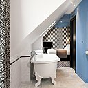 La modernité et la rigueur de l’espace sont contrebalancées par les formes anciennes de la baignoire à pieds et le côté rétro du carrelage.