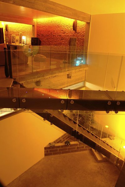 Une passerelle en verre, sans structure métallique, aux éléments intégrés dans la dalle en béton, traverse l’escalier et assure la circulation.